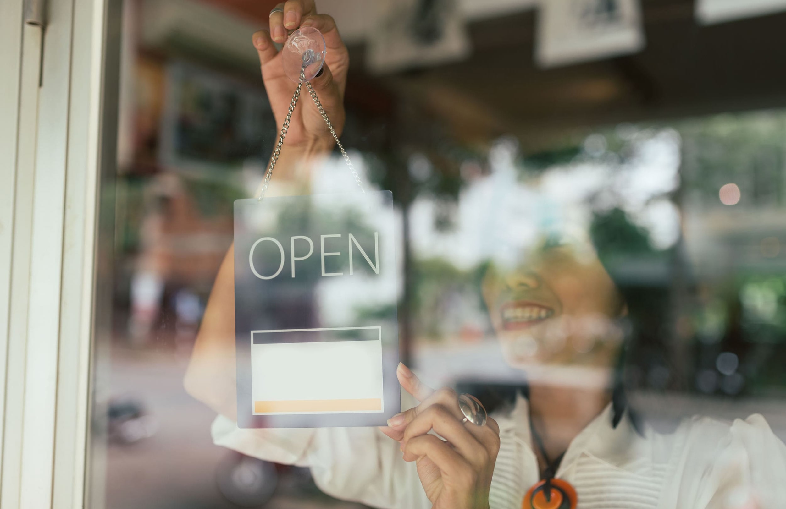 woman hanging open sign in store window