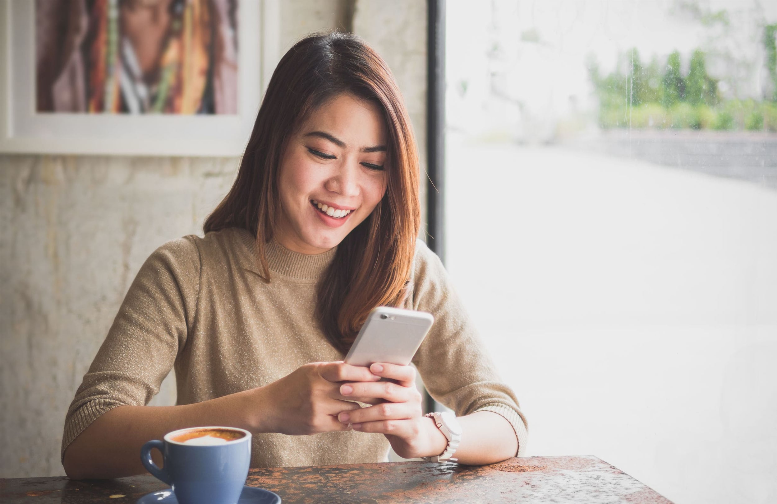 Woman smiling while typing on her mobile phone screen