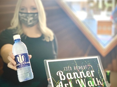 Western State Bank's Cassie Gonzales serves bottled water at Banner Art Walk