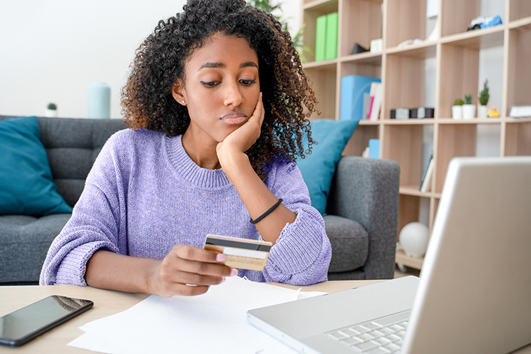 woman staring at debit card in dismay.